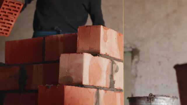 Worker placing bricks onto wall during masonry construction