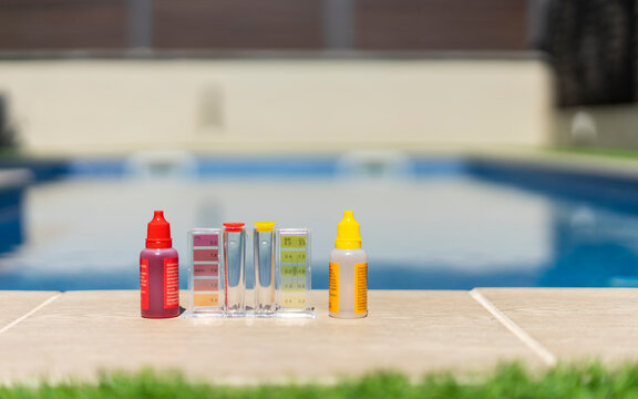 Close-up of a pool water testing kit with reagent bottles and color comparator, used for measuring pH and chlorine levels in a backyard swimming pool - pool maintenance concept