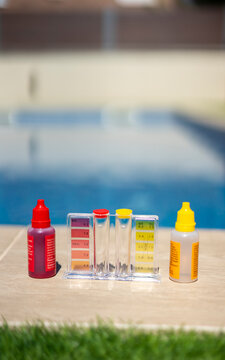 Close-up of a pool water testing kit with reagent bottles and color comparator, used for measuring pH and chlorine levels in a backyard swimming pool - pool maintenance concept