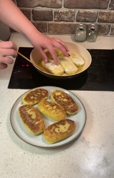 Perfect golden-brown crust! Close-up of flipping potato zrazy (stuffed potato pancakes) in a frying pan with oil. Cozy home cooking video.