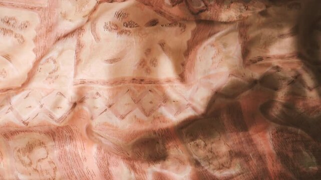 Natural silk fabric waving in the wind. Abstract background of moving waves. Beige and brown factory print pattern. Flowing textile with organic texture.