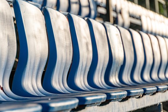 Blue bleacher seats at a sports stadium, extending into the distance under natural daylight a