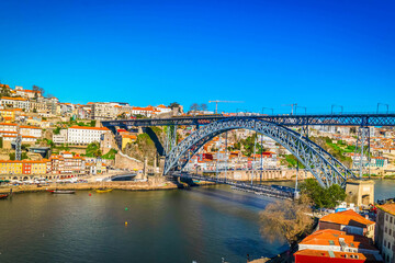 Fototapeta premium Picturesque, colorful view at old town Porto at bright day, Portugal with bridge Ponte Dom Luis over Douro river. Oporto, touristic mediterranean city