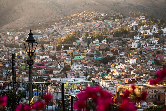 Colorful hillside view of Guanajuato Mexico at sunset with vibrant houses and distant mountains in a warm evening light