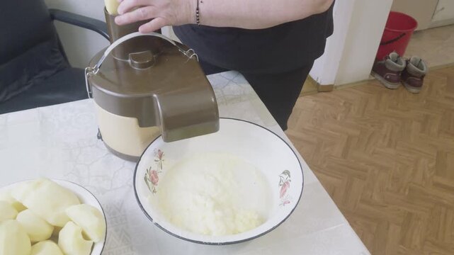 Electric Potato Grating Machine in Action: Traditional Preparation of Grated Potatoes for Lithuanian Cepelinai or Potato Pancakes.
