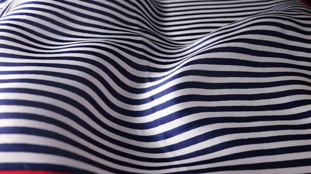 Blue and white striped silk fabric waving in the wind. Abstract background with smooth nautical pattern waves. Natural flowing textile motion for creative design projects.
