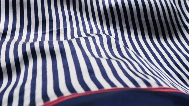 Close up of blue and white striped natural silk fabric waving in the wind. Abstract background with soft flowing waves of striped textile. Elegant nautical pattern material moving smoothly.