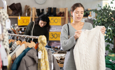 Fototapeta premium European happy young woman shopping sweaters in big store. Sale of clothing collection