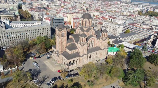 Drone moving backwards showing the monumental Saint Mark's Church and Belgrade panorama on a sunny day.