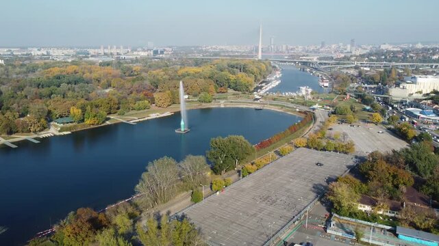 Sunny autumn day view of lake Ada Ciganlija with yellow trees and distant city view, Belgrade, Serbia.