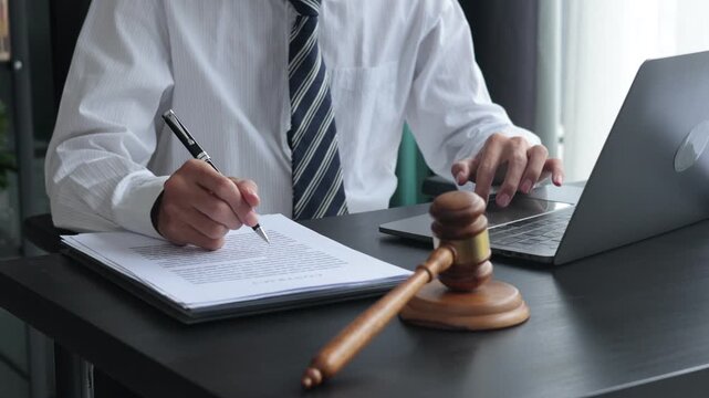 Lawyer working in office investigate the case by reading documents and using laptop.