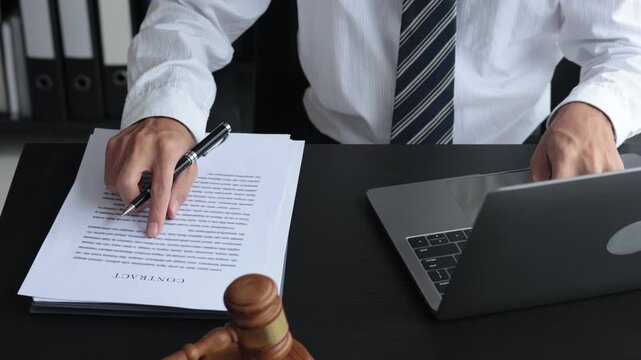 Lawyer working in office investigate the case by reading documents and using laptop.