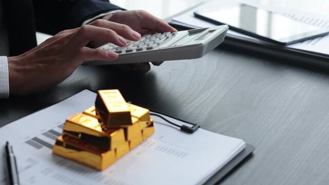 Gold volatility. Businessman calculating profit from fine gold bar investments.