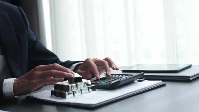 Silver Bullion Investment and Financial Analysis. Businessman Calculating Investment Returns with Silver Bars and Financial Documents.