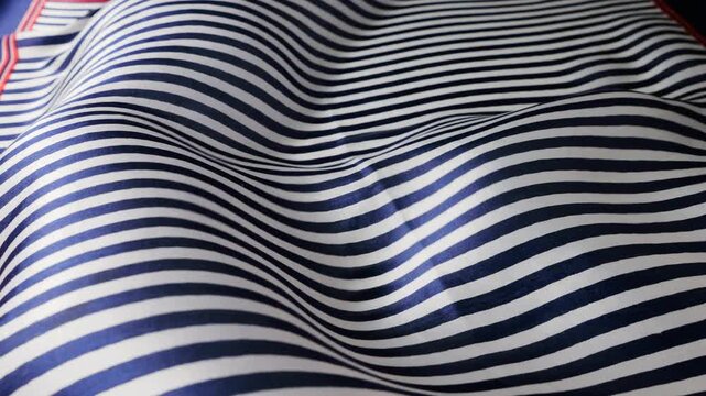 Abstract background with wavy natural silk fabric in motion. Blue and white striped pattern creates flowing texture. Soft ripples of silk cloth fluttering in the wind. 