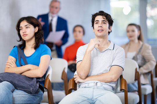 Mature male lecturer in background of classroom, address to youth listeners. Personal growth courses, professional orientation, overview lecture about educational institutions