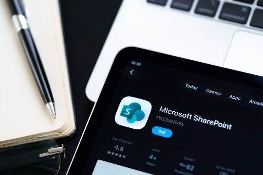 Microsoft SharePoint logo on iPad in Apple Liquid Glass iOS 26 interface photographed on desk with pen and laptop. Stafford, United Kingdom, April 13, 2026.