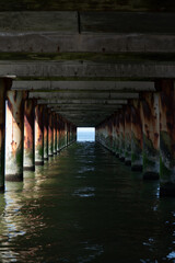 Fototapeta premium View under a pier with repeating supports over seawater