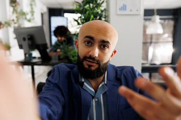 Naklejka premium Executive manager looking at camera while presenting project during video call on smartphone. Arab startup entrepreneur holding mobile phone and explaining strategy in online meeting