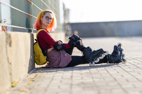 Young woman rollerblader resting on ground with colorful hair