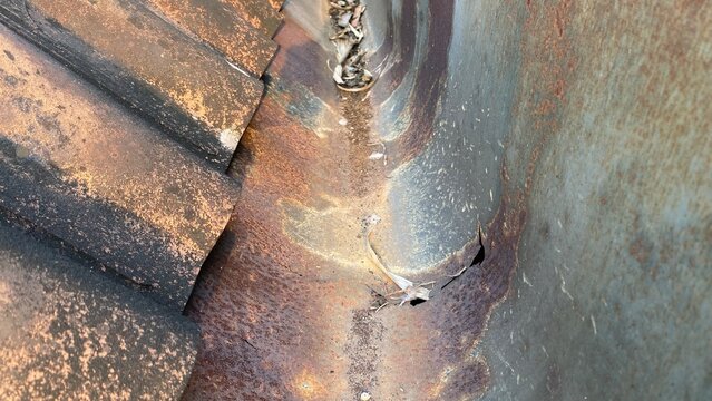 Damaged and Corroded Rain Gutter System on a Weathered Building Roof