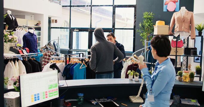 African american shoplifter wanting stole stylish clothes from modern boutique, being caught by asian employee. Bodyguard asking thief to return merchandise or will call the police. Crime concept