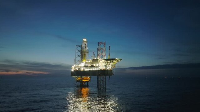 Aerial top view of offshore jack up rig and offshore platform during sunset for oil and gas exploration and production. 
