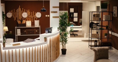 Naklejka premium Crane down shot of empty travel accommodation resort stylish lounge interior with cozy furniture and warm fireplace ready to welcome tourists. Modern hotel lobby with check in front reception desk
