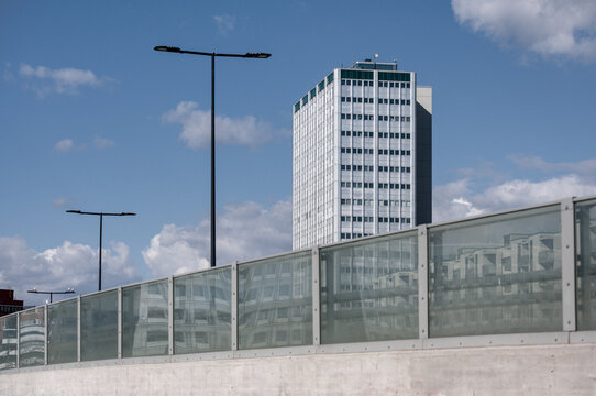 A modern high-rise office building rises above a glass barrier and streetlights