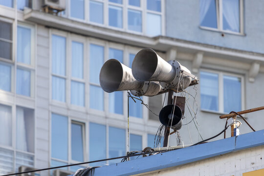 Old public address system with large horn loudspeakers on the roof of a city building. Emergency warning siren and outdoor communication equipment. Civil defense broadcast technology in urban area