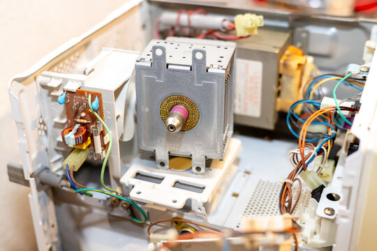 Internal view of a disassembled microwave oven showing magnetron and electronic circuits. Repairing household appliance and technical maintenance. Engineering of domestic electronic devices