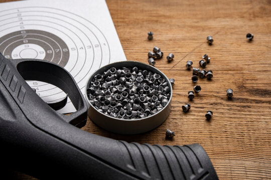 Airgun and pellet on wooden table.