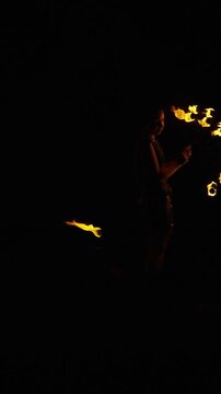 Dynamic night fire performance with spinning flames creating circular light trails around a silhouetted performer against a dark background in dramatic motion