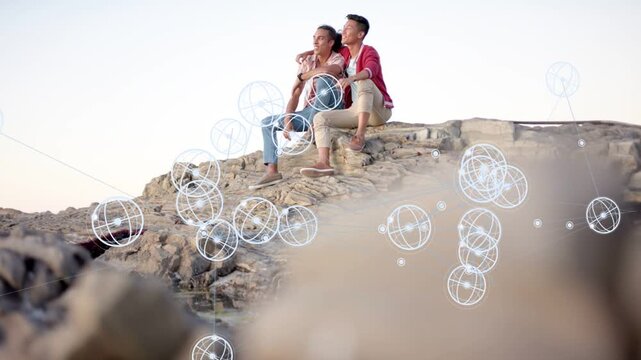 Camera pulling back men sitting rock pointing watching horizon white orbs drifting over them tech