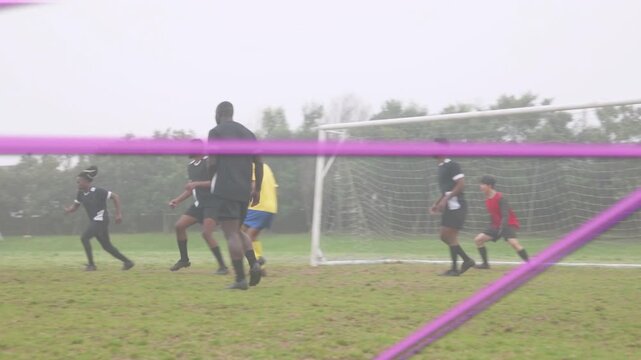 Soccer attacker yellow kit stepping, dribbling in box, jinking to bypass defenders, purple netting