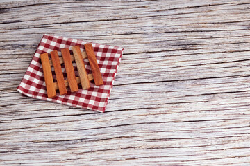 Fototapeta premium Mini Wooden pallets on checkered cloth. Rustic table beneath provides textured backdrop. Warm tones suggest cozy, vintage charm. Perfect for kitchen, bathroom, or home decor scenes