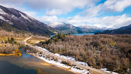Aerial winter view of Ruta 40 running between Lake Villarino and Lake Falkner through bare lenga forest with snowy Andes ahead. © Marcio Eneas