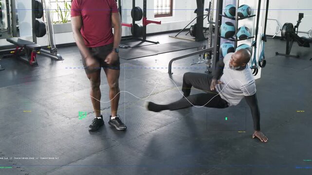 Trainer shifting weight onto hands and demonstrating kick-through in gym, coaching trainee