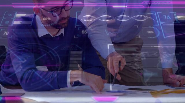 Standing man pointing pen triggers HUD overlay while seated man annotating charts for tech review
