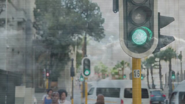 Foreground traffic signal changing green to red causing cars braking while people walking transport