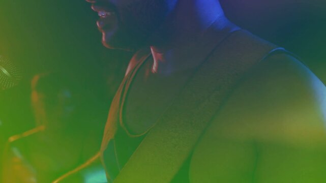 Drummer striking drum, cam pulling back revealing singer leaning into mic, performing song in haze