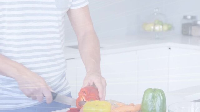 Man placing board and reaching for chef's knife, slicing red pepper for meal prep in kitchen