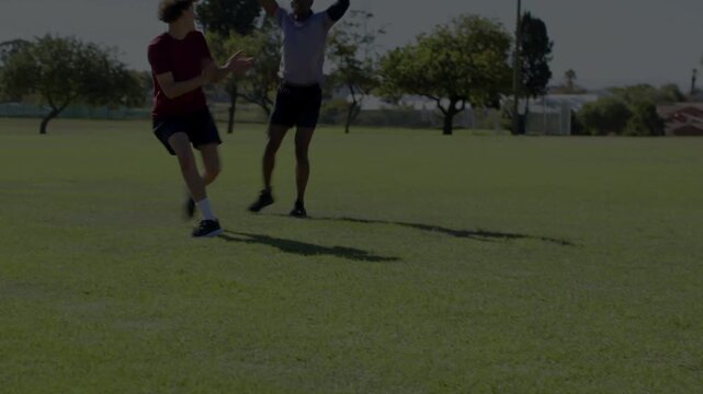 Man in red shifting, lunging as player coming, falling and hugging as mates joining sports practice