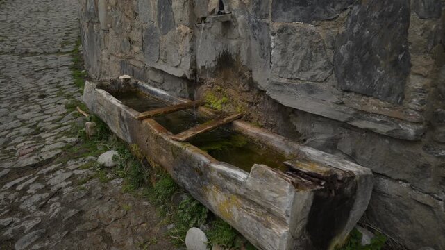 Traditional wooden water trough with flowing water