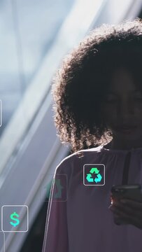 Vertical video: Woman holding phone at glass wall tapping and showing eco finance icons over torso