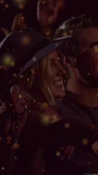 Vertical video: Woman in hat leaning, phone catching music light to record and gold dust over crowd