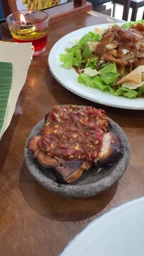 pecak cucut is a traditional Indonesian dish from Pekalongan, made with smoked or fried shark, served with spicy red sambal of chili, shrimp paste, tomato, and shallots, creating a rich, tender flavor