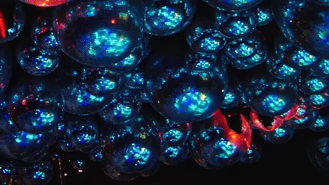 Experience vibrant energy of Christmas celebration. Numerous disco balls reflect kaleidoscope of red, blue, and orange lights, creating magical atmosphere on festive night at lively nightclub.