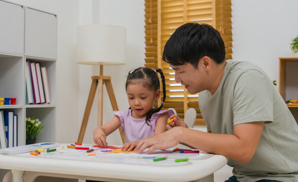 Caption/Description: father and child girl drawing and painting with colorful oil pastels on paper