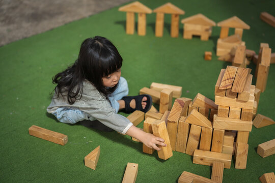 preschool child girl playing with wooden toy block at outdoor